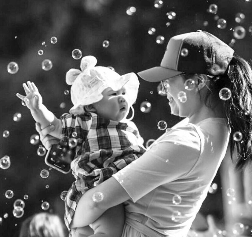 A parent and child play together among floating bubbles